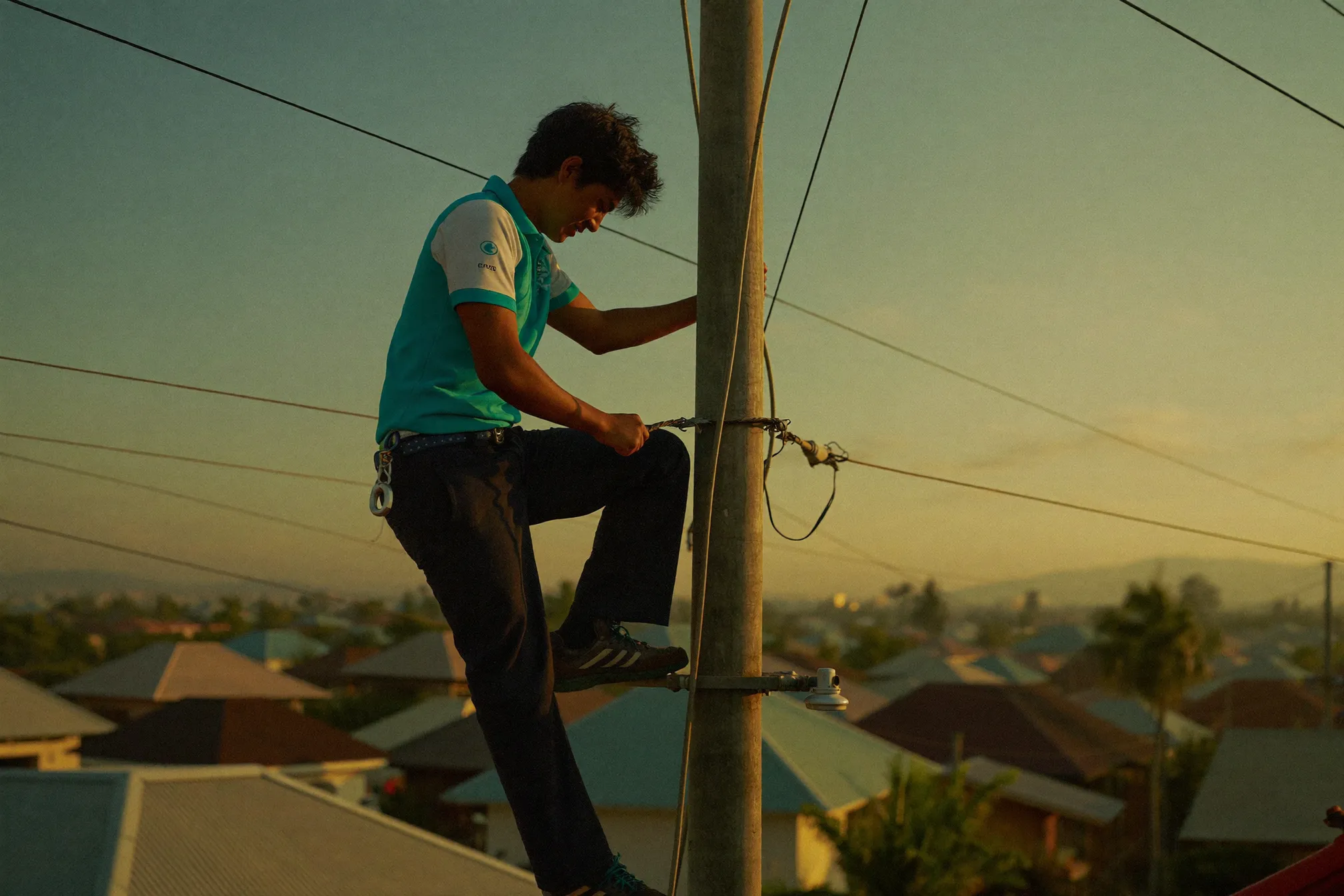 Fiber technician connecting a cable on a utility pole at golden hour
